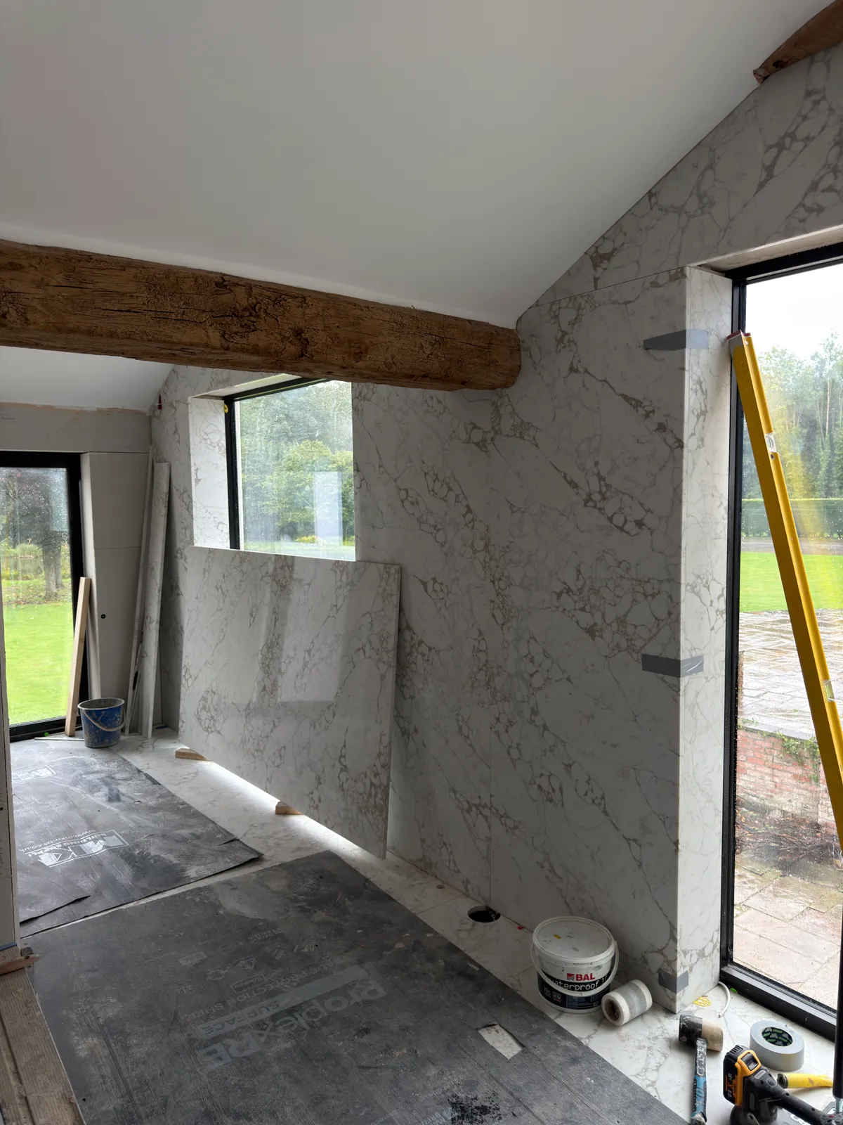 Quartz slab installation in progress beneath exposed timber beams in the Knutsford bathroom.