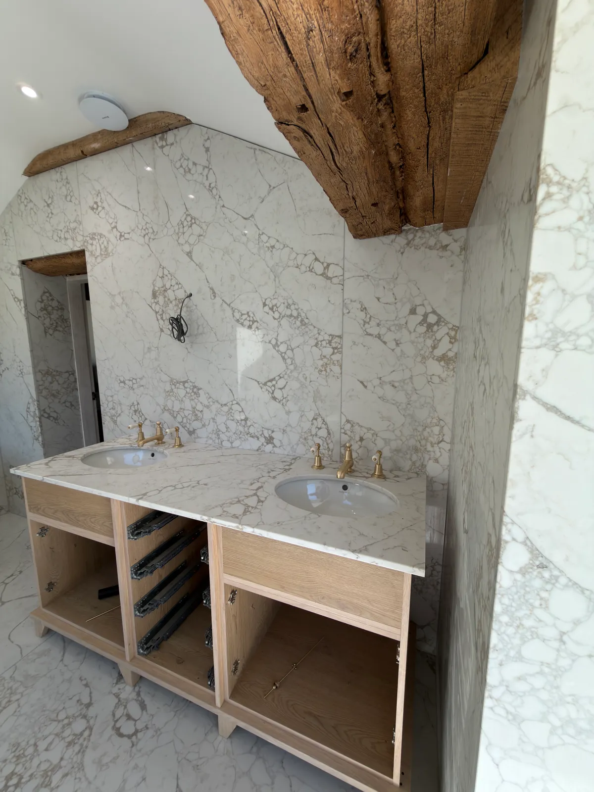 A double basin vanity beneath pale veined quartz walls and exposed timber in the Knutsford bathroom.