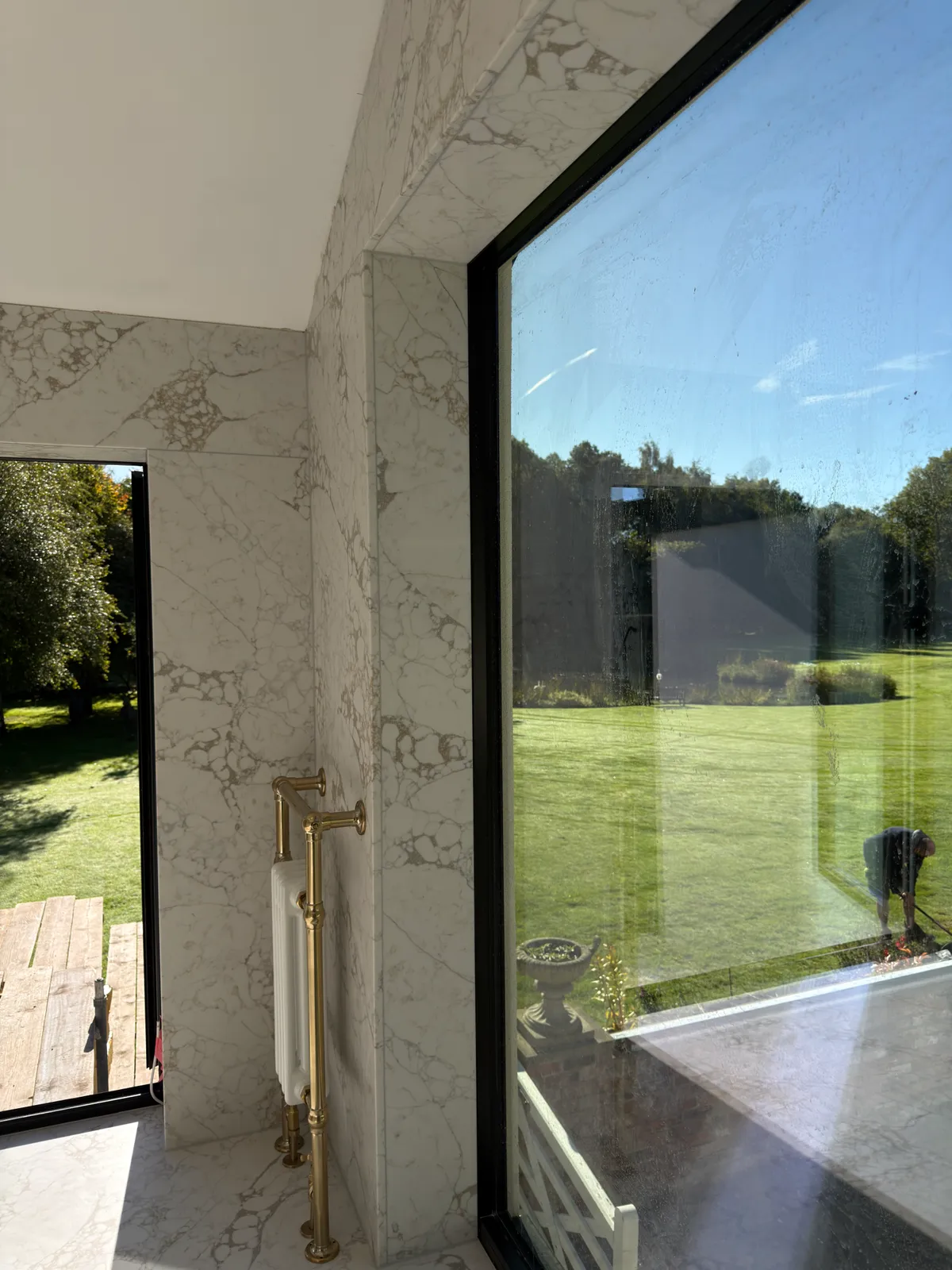 Quartz slab detailing around a window beside a gold coloured radiator in the Knutsford bathroom.