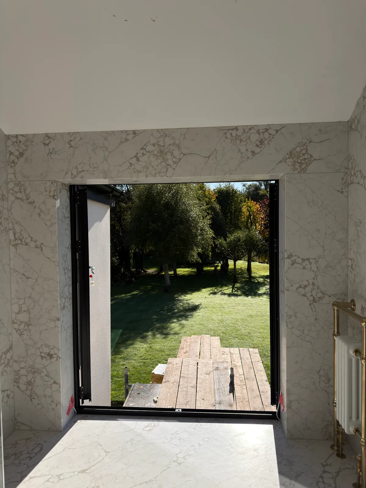 Pale veined quartz slabs around a tall glazed opening in the Knutsford bathroom.